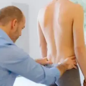 Physiotherapeut untersucht Rücken eines Patienten in Praxis, Rückenschmerzen Behandlung