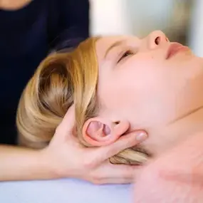 Frau erhält Nackenmassage in Praxis, Physiotherapie und Entspannung pur