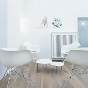 Minimalistischer Wartebereich mit weißen Designstühlen und Couchtischen