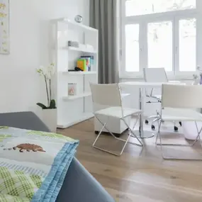 Helles Arztzimmer mit Untersuchungsliege, Schreibtisch und Wartebereich
